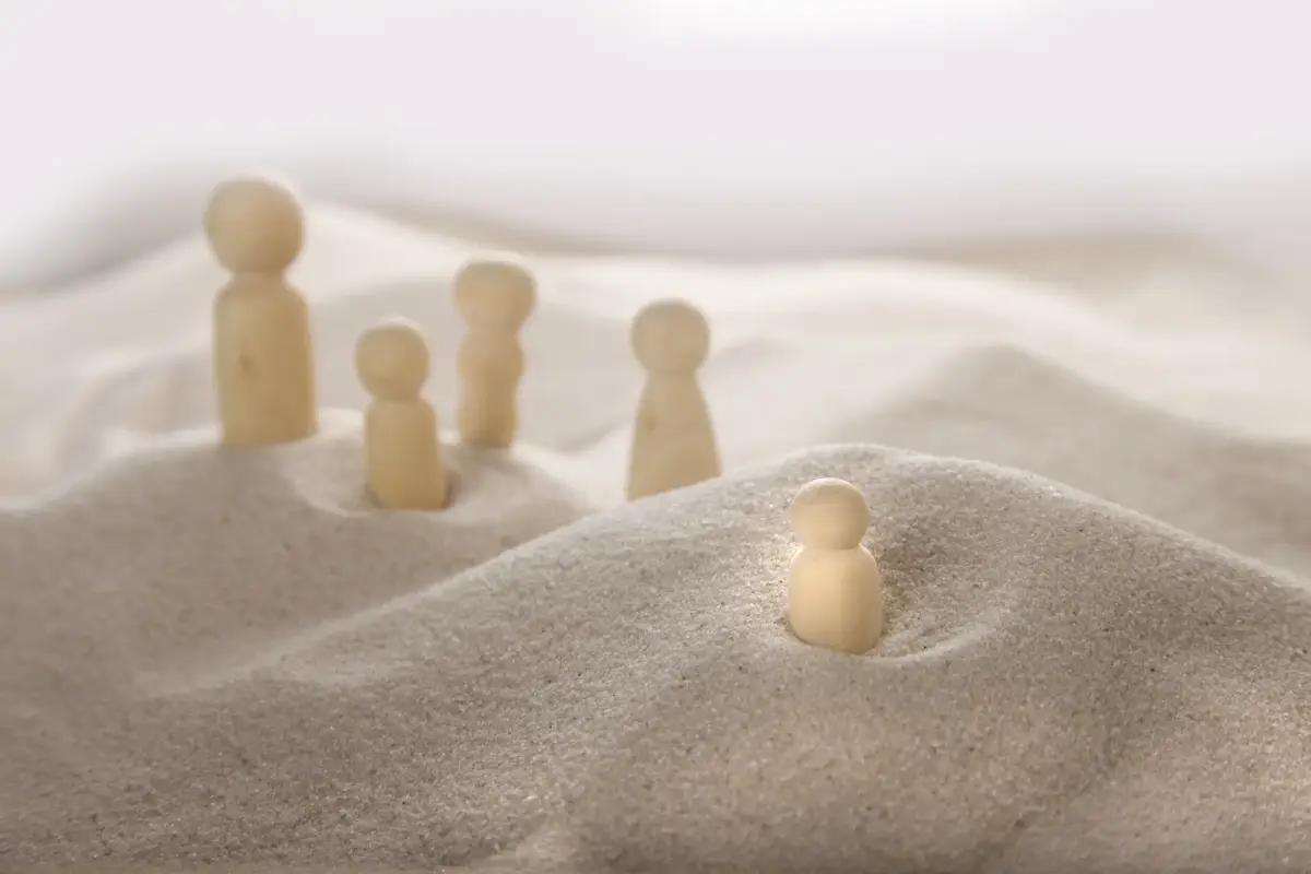 Holzfiguren einer systemischen Aufstellung im Sand
